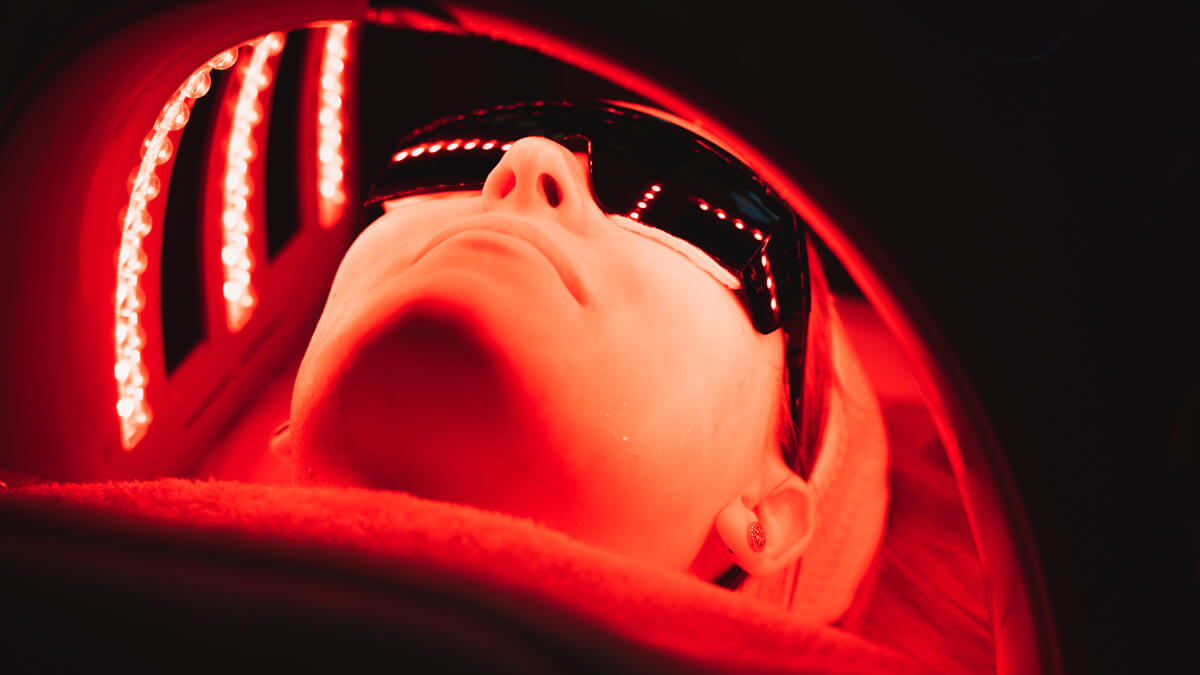 Woman under red LED light therapy at Purify Skincare Clinic