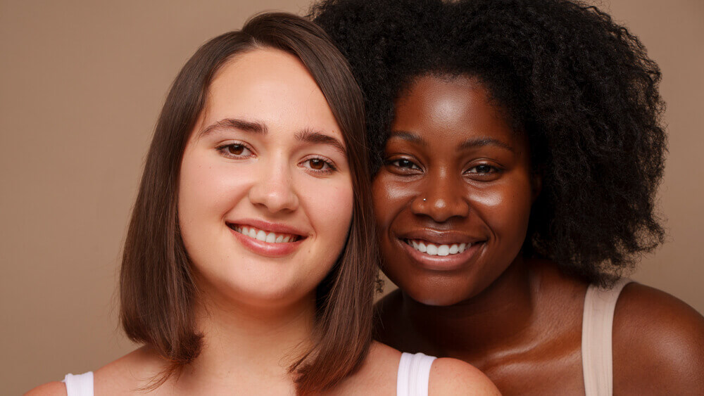 Two women with different skin tones smiling