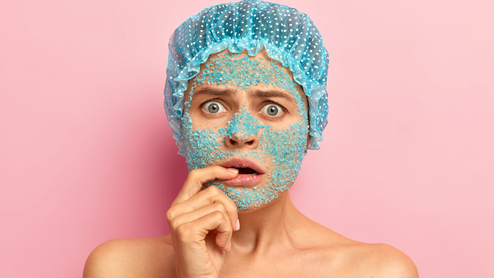 Surprised woman applies blue sea salt mask