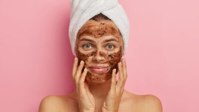 Young lady applies coffee scrub face with hands