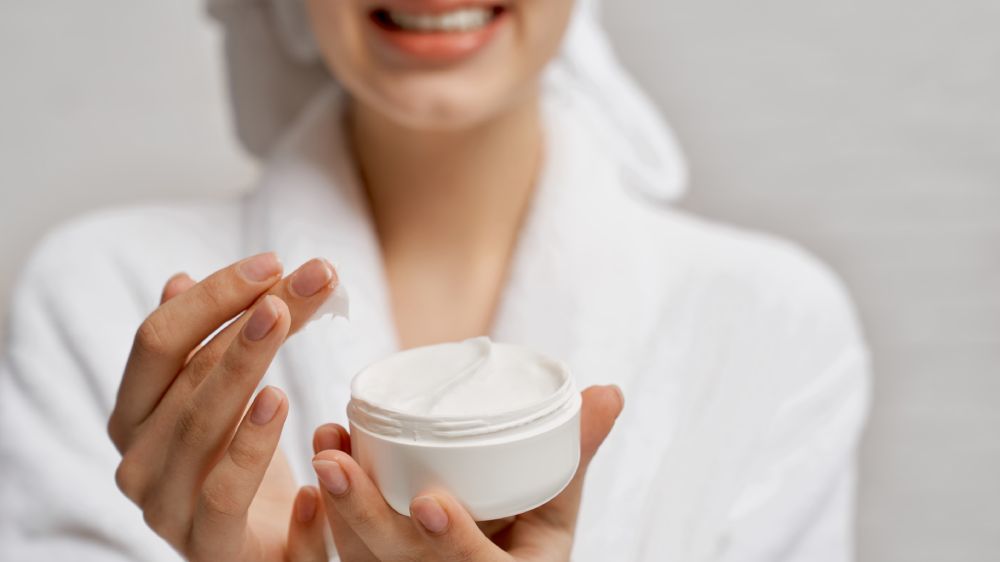 Young woman holding moisturizer