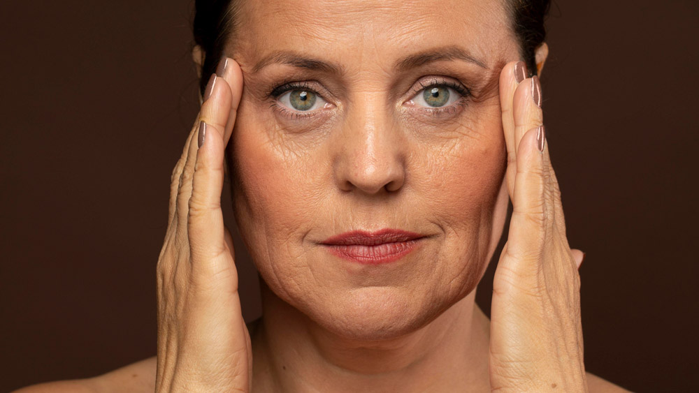 Elder woman with make up posing while holding her temples