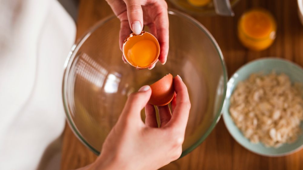 Hands separating egg's white and yolk in a bowl