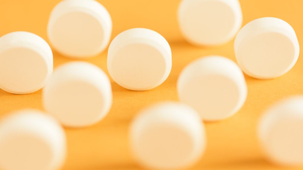 Round circular white pills standing on a yellow background