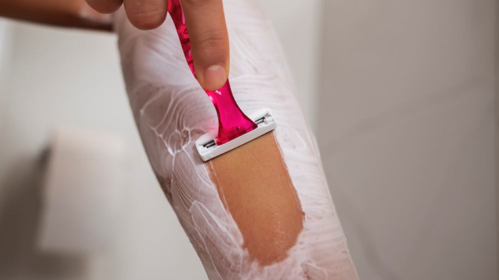 Side view of a woman shaving her leg