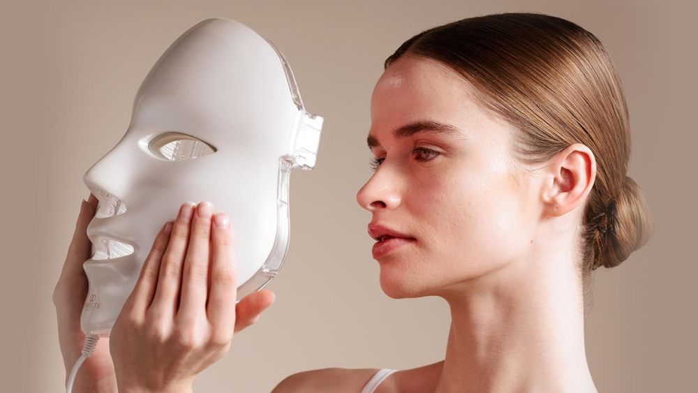 Young woman keeping LED face mask in hand